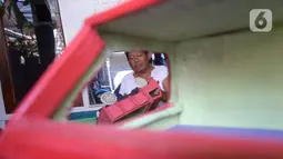 Perajin Uus Saputra (58) menyelesaikan mobil mainan dari limbah kayu bekas di Kelurahan Ciputat, Tangerang Selatan, Banten, Rabu (28/10/2020). Mobil mainan yang menggunakan bahan baku kayu tersebut dijual seharga Rp 50 ribu hingga Rp 250 ribu tergantung ukuran. (merdeka.com/Dwi Narwoko)