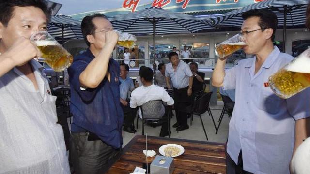 Sekelompok pria minum bir selama festival di Korea Utara. Mereka merayakan janji Kim Jong Un untuk memperbaiki standar hidup dan membangun bangsa (AP)