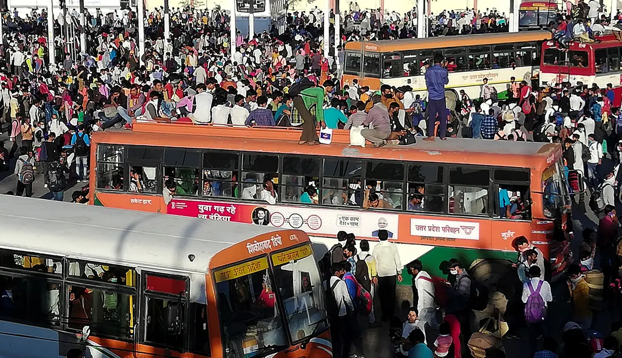 Pekerja migran dan anggota keluarga mereka berkumpul di luar terminal bus Anand Vihar untuk pulang ke kampung halamannya, di New Delhi, Sabtu (28/3/2020). Ribuan orang meninggalkan New Delhi setelah pemerintah India memberlakukan lockdown untuk mencegah penyebaran COVID-19. (Bhuvan BAGGA/AFP)