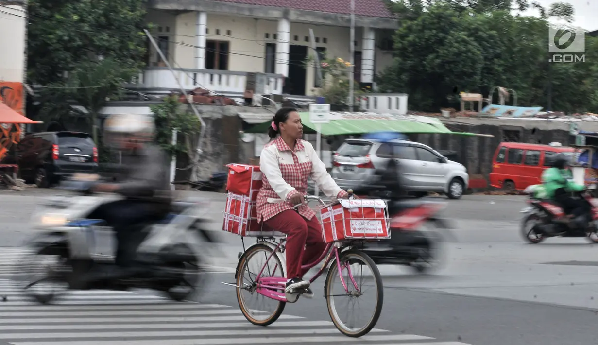 Pedagang minuman saat dengan hati-hati menyeberangi jalan di persimpangan Terminal Pulo Gadung, Jakarta, Rabu (5/9). Menurut warga, kecelakaan sering menimpa pengendara dan pejalan kaki. (Merdeka.com/Iqbal Nugroho)