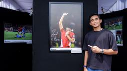 Pemain Timnas Indonesia, Rizky Ridho berfoto bersama dengan karya foto milik Ady Sesotya yang memperlihatkan dirinya tengah berselebrasi mencium logo garuda di jerseynya setelah Skuad Garuda menang 1-0 atas Bahrain di Kualifikasi Piala Dunia 2026 saat pameran foto Media Cup 2025 bertema "Timnas Indonesia dari Masa ke Masa" di Cibis, Cilandak, Jakarta Selatan, Selasa (28/10/2025). (Bola.com/Bagaskara Lazuardi)