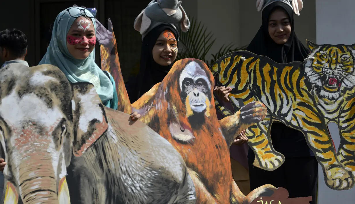 Sejumlah pelajar membawa gambar binatang saat melakukan aksi demonstrasi dalam peringatan Hari Bumi Sedunia di Banda Aceh (22/4). Dalam aksinya para pelajar tersebut membuat karya-karya berupa gambar satwa Indonesia, seperti, orangutan, gajah dan harimau. (AFP Photo/Chaideer Mahyuddin)