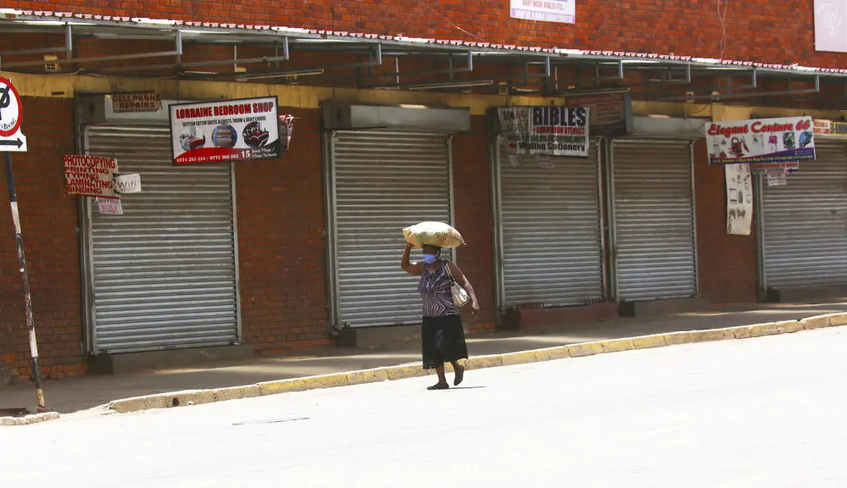 Seorang wanita berjalan di jalan yang sepi di Harare, Zimbabwe, Selasa (5/1/2021). Zimbabwe memulai lockdown selama 30 hari dalam upaya untuk mengendalikan lonjakan infeksi COVID-19 yang mengancam petugas kesehatan. (AP Photo/Tsvangirayi Mukwazhi)