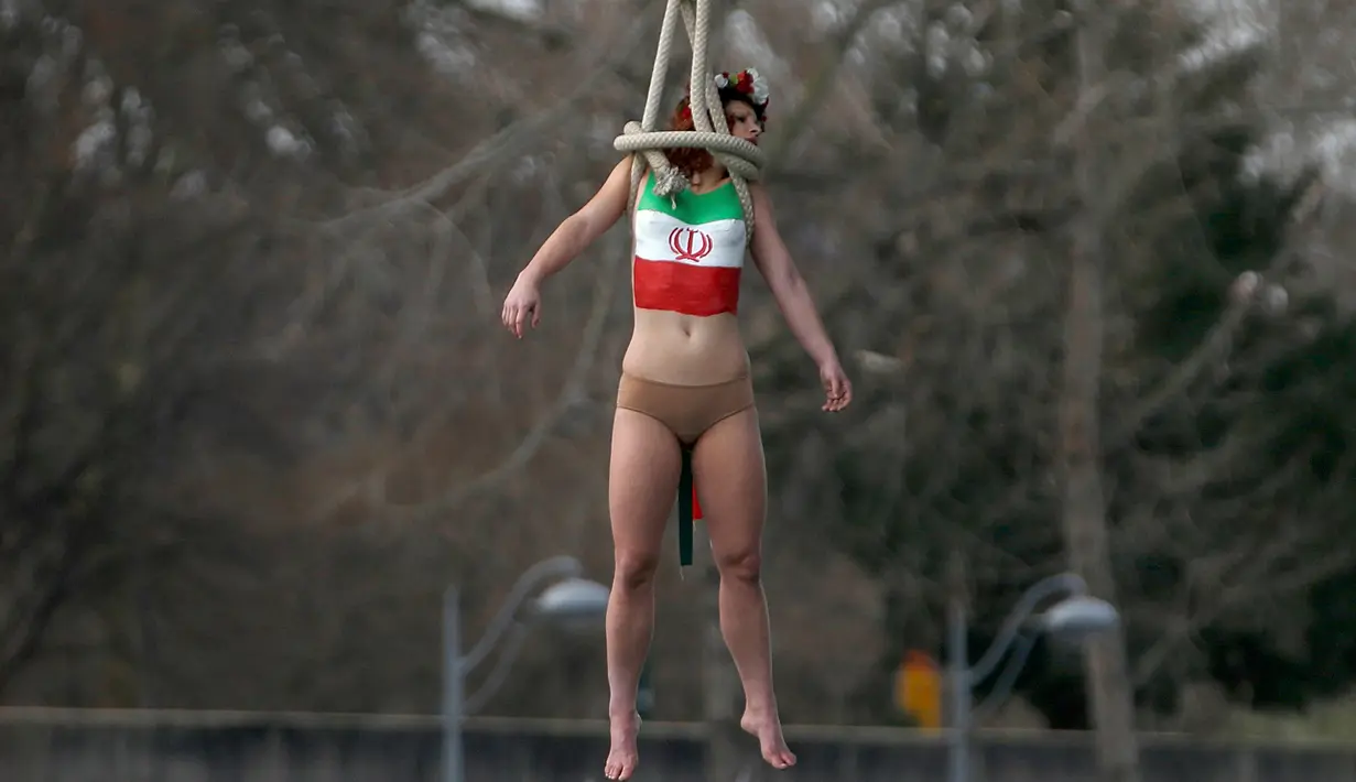 Seorang aktivis dari organisasi hak-hak perempuan Femen melakukan aksi bergelantungan dari sebuah jembatan di Paris, Prancis, Kamis (28/1). Mereka menggelar protes atas kunjungan Presiden Iran, Hassan Rouhani ke Paris. (REUTERS/Charles Platiau)