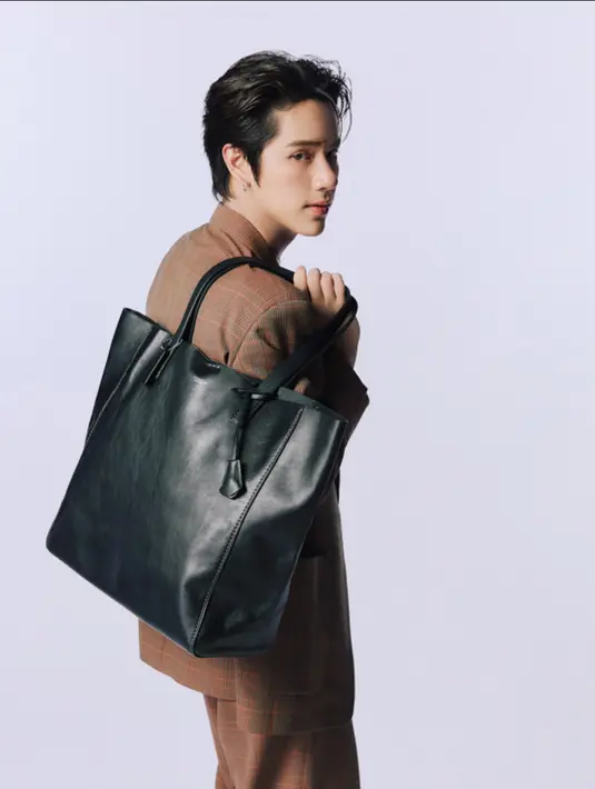 <p>Nanon tampil mengenakan broadway tote bag hitam dipadukan setelan coklat dengan jas dan celana panjangnya. [dok. Coach]</p>