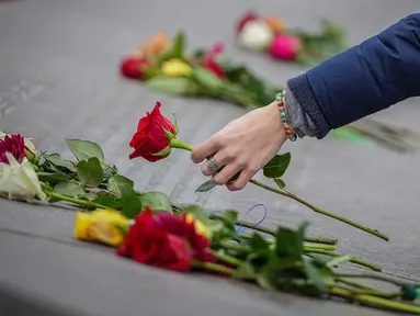 Kelli Muster dari Santa Rosa, California meletakkan bunga mawar merah di Columbine Memorial di Clement Park pada peringatan 25 tahun penembakan di sekolah tersebut pada 20 April 2024 di Littleton, Colorado. (Marc Piscotty/Getty Images North America/Getty Images via AFP)