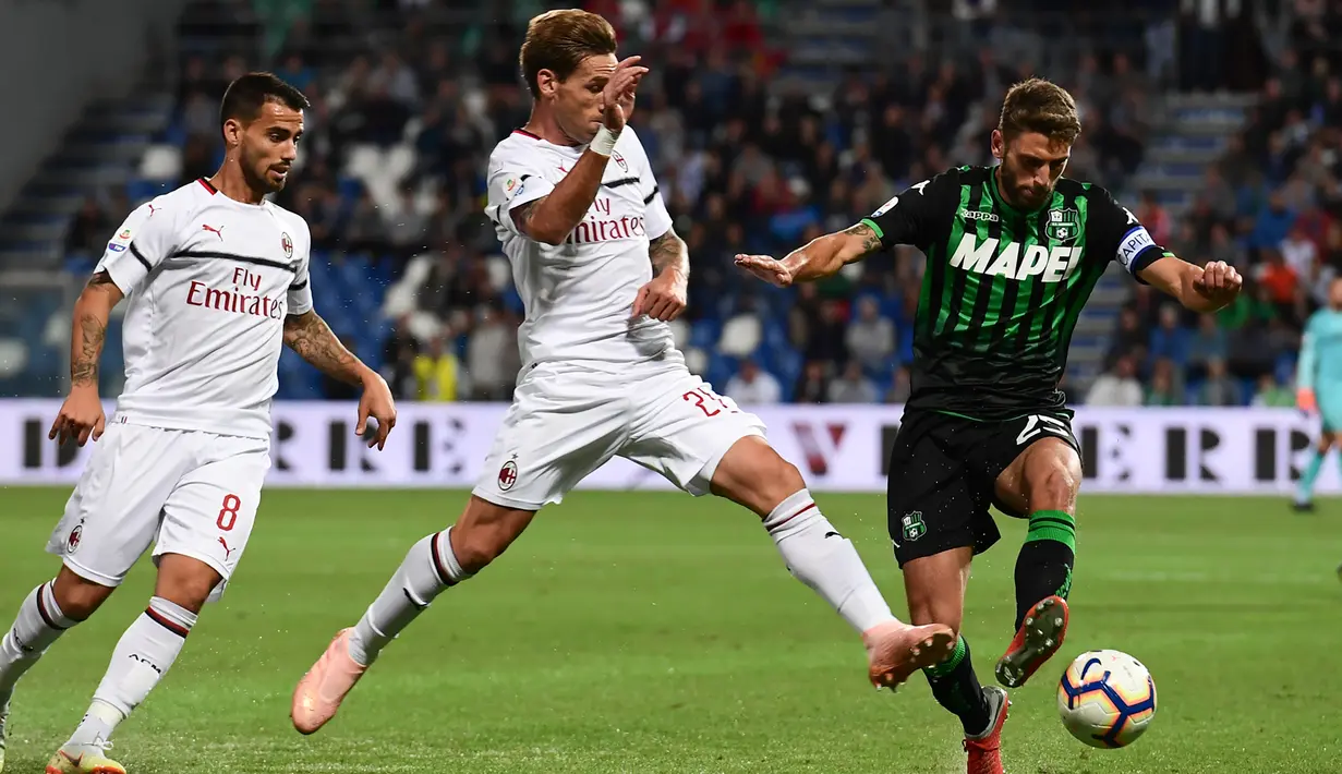 Gelandang AC Milan, Lucas Biglia (tengah) berusaha merebut bola penyerang Sassuolo, Domenico Berardi saat bertanding pada lanjutan Liga Italia di Stadion Mapei, Reggio Emilia (30/9). AC Milan menang telak 4-1 atas Sassuolo. (AFP Photo/Miguel Medina)
