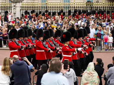 Orang-orang menyaksikan prosesi pergantian penjaga di Istana Buckingham, London, Senin (23/8/2021). Pergantian pasukan jaga yang dilengkapi dengan alat musik lengkap ala marching band tersebut berlangsung untuk pertama kalinya sejak dimulainya pandemi corona Covid-19. (AP Photo/Alberto Pezzali)