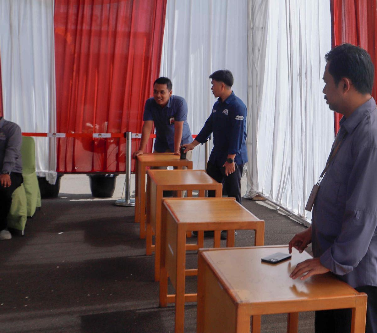 Beberapa petugas tampak sedang berdiri di depan 4 meja cokelat yang menjadi tempat untuk menaruh bilik suara. Foto: liputan6.com / Herman Zakharia<br>