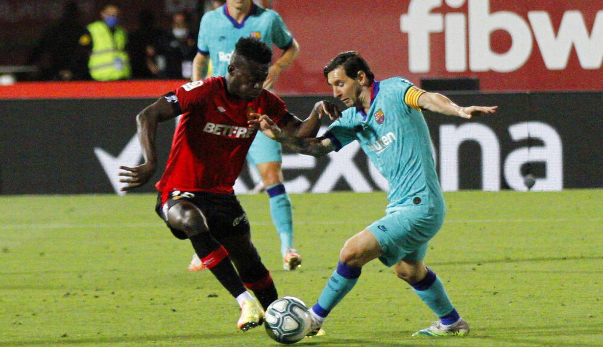 Striker Barcelona, Lionel Messi, berusaha melewati pemain Mallorca, Iddrisu Mohamed, pada laga La Liga di Estadio de Son Moix, Minggu (14/6/2020). Barcelona menang dengan skor 4-0. (AP/Francisco Ubilla)