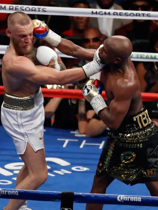 Floyd Mayweather dan Conor McGregor saling pukul saat pertandingan tinju super kelas welter di Las Vegas (26/8). Dalam pertandingan ini Mayweather menang TKO di ronde kesepuluh. (AP Photo/Isaac Brekken)