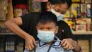 Seorang wanita membantu siwa bersiap untuk hari pertama kelas tatap muka di sekolah dasar Comembo di kota Makati, Filipina, Senin (6/12/2021). Beberapa sekolah di Manila diizinkan dibuka kembali setelah berbulan-bulan lamanya karena kasus COVID-19 terus menurun. (AP Photo/Aaron Favila)
