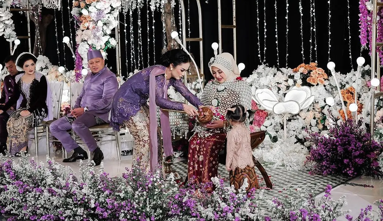 Krisdayanti juga tampak menghadiri acara Mitoni Aurel Hermansyah ini. Krisdayanti tampil anggun dalam balutan kebaya cantik berwarna ungu. Kebaya kutubaru ini juga memiliki bordir floral diberi payet-payet yang membuat penampilan Krisdayanti semakin berkilauan. Krisdayanti memadukan penampilannya dengan kain batik cantik yang serasi dan selendang ungu polos. [Foto: Instagram/attahalilintar]