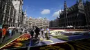 Para sukarelawan bekerja menempatkan bunga begonia ke dalam karpet bunga raksasa bertema Art Nouveau di Grand Place yang bersejarah di Brussels, Belgia, Kamis, 15 Agustus 2024. (AP Photo/Virginia Mayo)