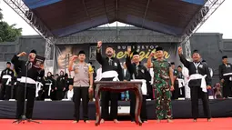 Anam Ardiansyah (kiri) memimpin Deklarasi Pemilu Damai diikuti Bupati Ponorogo Ipong Muchlissoni (tengah) dan 45.024 pesilat PSHT dari 307 desa dan kelurahan di Alun-alun Ponorogo, Jawa Timur, Minggu (30/12). (Liputan6.com/HO/Firdaus)
