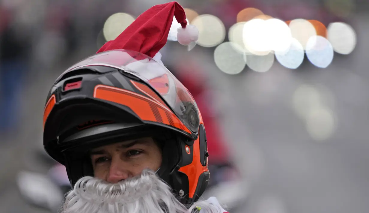 Seorang pengendara yang mengenakan kostum Sinterklas mengendarai motor selama parade Sinterklas di Beograd, Serbia, Minggu (26/12/2021). Mereka melakukan konvoi menuju rumah sakit anak-anak untuk membagikan mainan hadiah Natal kepada pasien di sana. (AP Photo/Darko Vojinovic)