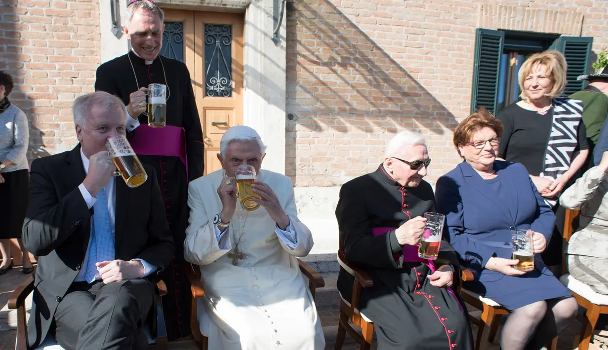 Paus Emeritus Benediktus XVI meminum segelas bir bersama Perdana Menteri Bavaria Horst Seehofer saat merayakan ulang tahunnya yang ke-90 di Vatikan (17/4). (L'Osservatore Romano/Pool Photo via AP)