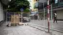 Seorang wanita melewati barikade improvisasi yang terbuat dari panggangan untuk membatasi pergerakan warga di Hanoi, pada 30 Agustus 2021. Tiang bambu, peti bir, tangga dan kursi rusak: benda sehari-hari membentuk barikade sementara di jalan-jalan saat lockdown Covid-19. (Manan VATSYAYANA/AFP)