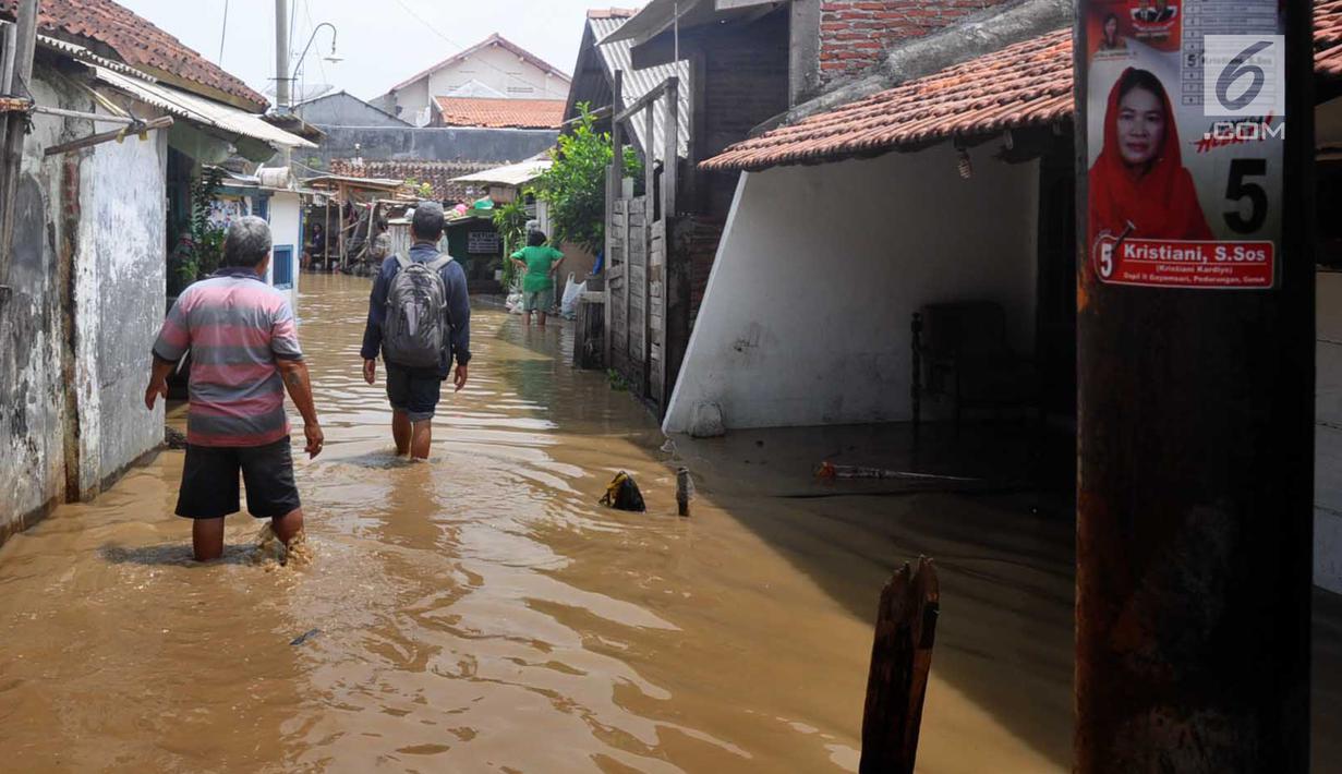 Sejumlah warga melintasi genangan banjir di kawasan Sawah besar Semarang, Jawa Tengah, Sabtu (8/12). Ratusan rumah tergenang banjir akibat Tanggul Sungai Banjir Kanal Timur jebol. (Liputan6.com/Gholib)