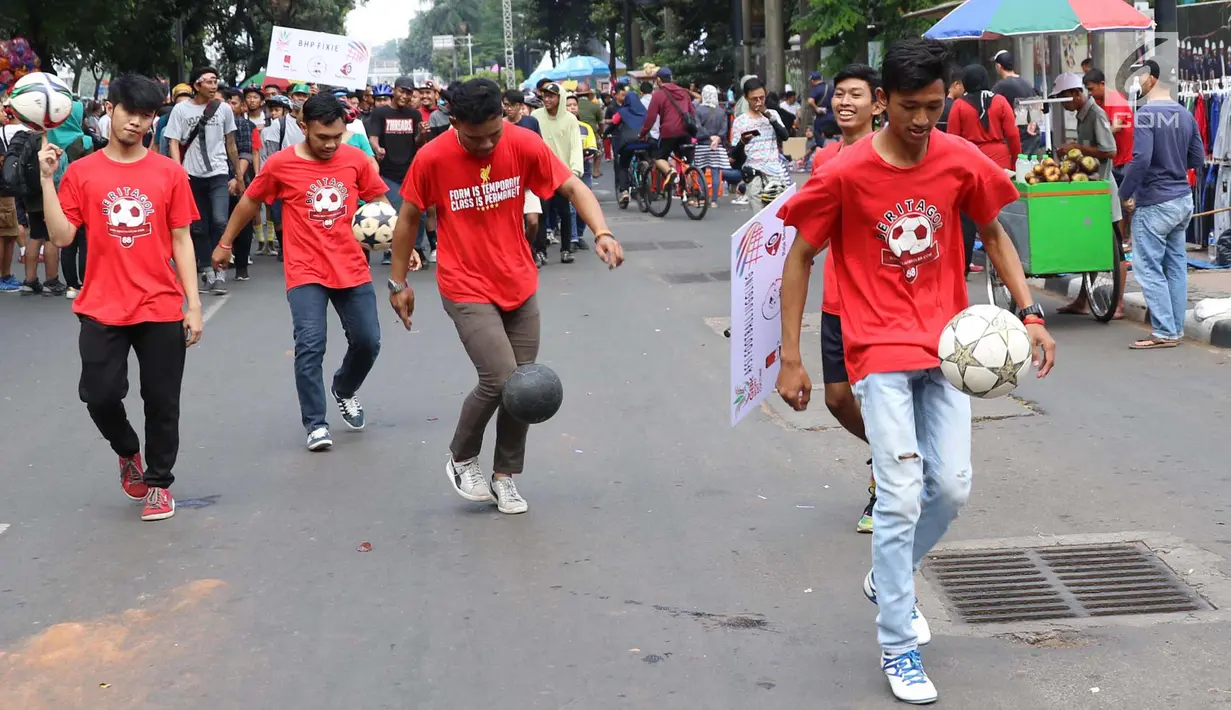 Aksi sejumlah pria memainkan bola saat melakukan karnaval di jalan Pintu 1 Senayan, Jakarta, Minggu (24/9). Karnaval tersebut dilakukan dalam rangka HUT Gelora Bungkarno yang ke-55. (Liputan6.com/Angga Yuniar)