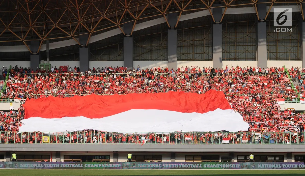 Suporter Timnas Indonesia membentangkan bendera raksasa jelang menyaksikan laga persahabatan antara Indonesia melawan Fiji di Stadion Patriot Candrabhaga, Bekasi, Sabtu (9/2). Laga berakhir imbang 0-0. (Liputan6.com/Helmi Fithriansyah)