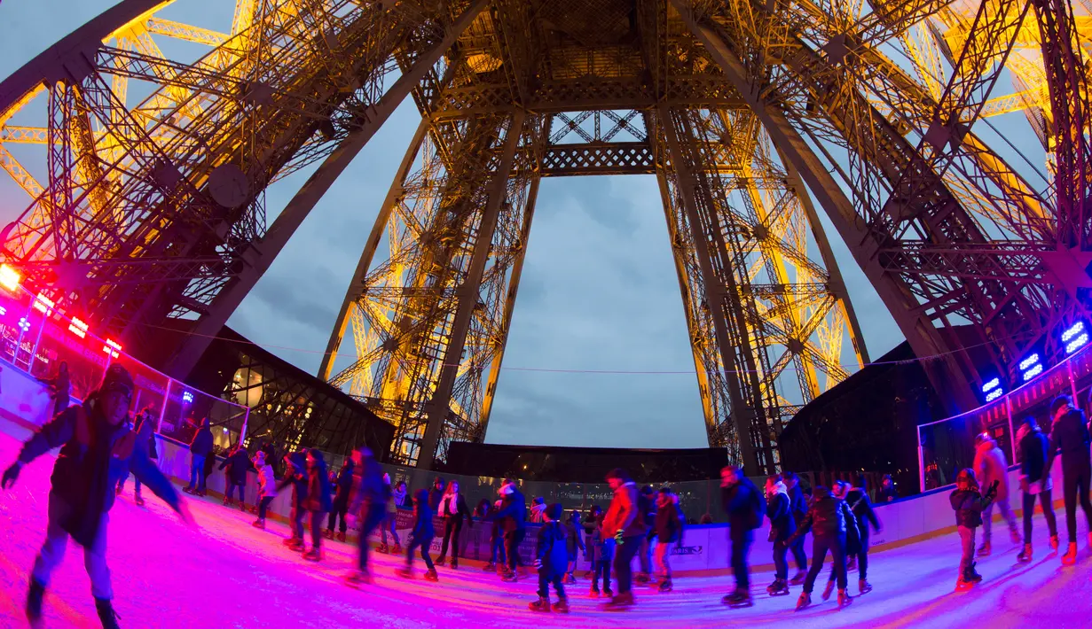 Suasana saat wisatawan tengah asyik bermain ice skating di sebuah arena yang dibuka di lantai 1 Menara Eiffel, Paris, 19 Desember 2016. Arena seluncur es seluas 185 meter persegi berada di ketinggian 57 meter dari permukaan tanah. (AFP PHOTO/JOEL SAGET)