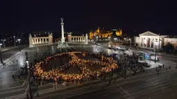 Orang-orang membuat tanda perdamaian dengan lampu saat demonstrasi untuk Ukraina yang diselenggarakan oleh Greenpeace di Heroes Square, Budapest, Hungaria, 9 Maret 2022. Lebih dari 1,5 juta orang telah menyeberang dari Ukraina ke negara-negara tetangga. (AP Photo/Anna Szilagyi)