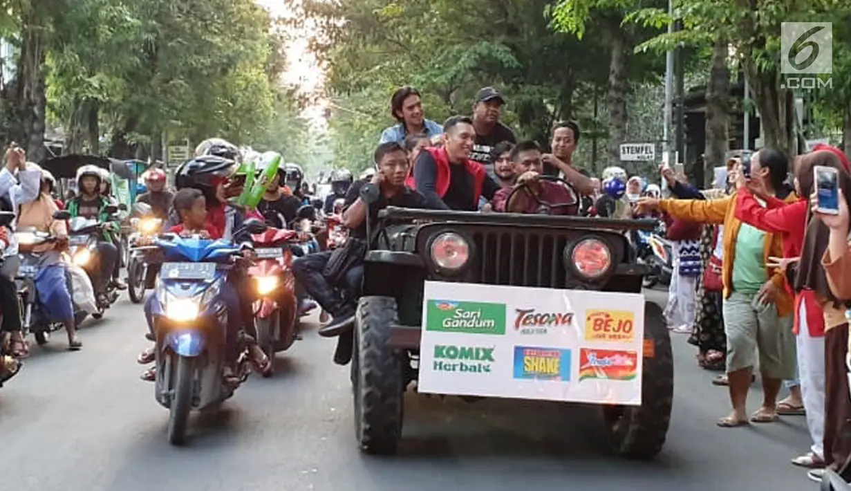 Pengisi acara Karnaval SCTV menyapa warga saat mengikuti pawai artis keliling Kota Bojonegoro, Jawa Timur, Sabtu (30/3). Karnaval SCTV di Bojonegoro berlangsung pada 30-31 Maret 2019. (Liputan6.com/Pool/SCTV)