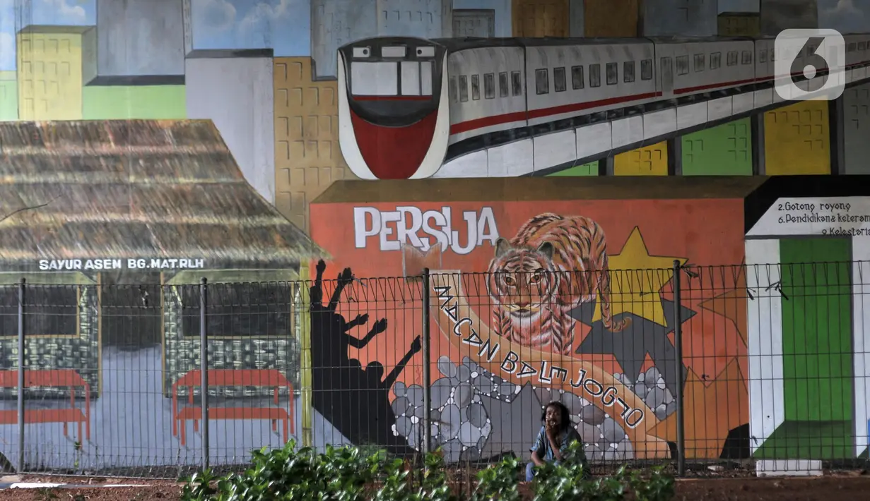 Seorang pria duduk dekat mural bertema Jakarta Masa Kini di Taman Betawi kolong Tol JORR W-2, Joglo, Jakarta Barat, Minggu (17/11/2019). Lahan kosong di kolong tol itu disulap menjadi taman bernuansa Betawi dilengkapi saung, musala, arena bermain serta hiasan mural 3D. (merdeka.com/Iqbal Nugroho)