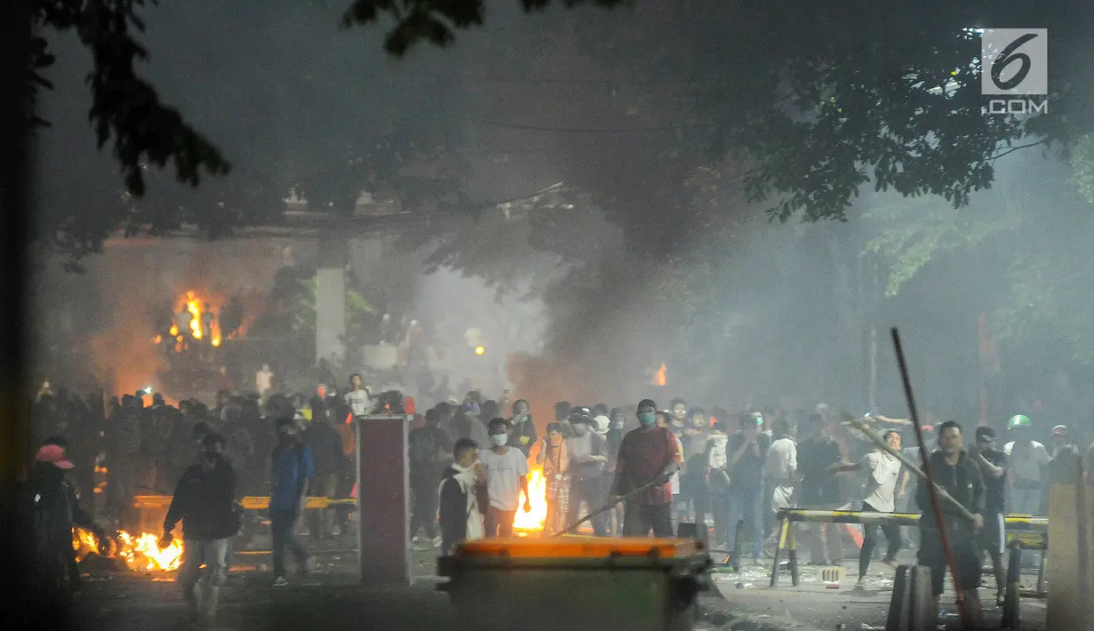 Massa aksi melempar benda ke arah barikade Polisi di kawasan Tanah Abang, Jakarta Pusat, Rabu (22/5/2019). Massa terus melakukan perlawanan meski polisi menembakkan gas air mata pasca buntut dari unjuk rasa hasil penghitungan suara Pemilu 2019 di depan kantor Bawaslu. (Liputan6.com/Herman Zakharia)