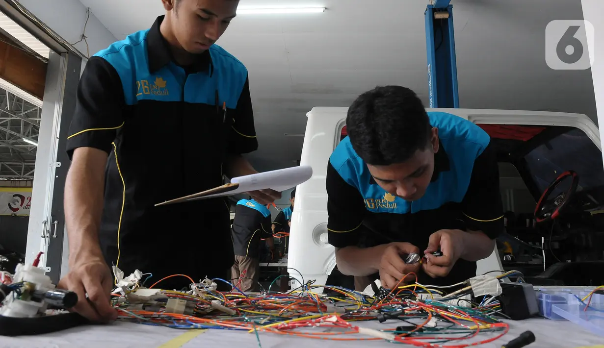Pelajar SMK Negeri 26 Jakarta melakukan pengecekan instalasi part konversi mobil listrik di Bengkel Otomotif SMKN 26, Jakarta, Rabu (13/5/2023). (merdeka.com/Imam Buhori)