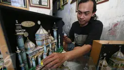 Seorang perajin, Albani, menyelesaikan mahar pernikahan berbentuk miniatur masjid, di dusun Jotowang, Yogyakarta, Rabu (15/6). Pada Ramadan, pemesanan miniatur masjid berbahan dasar uang pecahan rupiah itu mengalami peningkatan (Liputan6.com/Boy Harjanto)