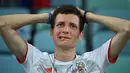 Seorang suporter Rusia terlihat kecewa setelah tim kesayangannya kalah dari Kroasia pada laga perempat final Piala Dunia 2018 di Stadion Olimpiade Fisht, Sabtu (7/7). Tuan rumah Rusia tumbang lewat adu penalti melawan Kroasia 3-4. (Kirill KUDRYAVTSEV/AFP)