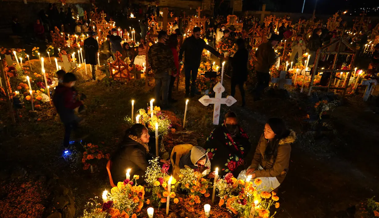 Kerabat menghabiskan malam di samping makam orang tercinta pada perayaan Hari Kematian di pemakaman Arocutin, Michoacan, Meksiko, 1 November 2021. Pada Hari Kematian, kerabat menghabiskan malam di samping makam orang yang mereka cintai. (AP Photo/Eduardo Verdugo)