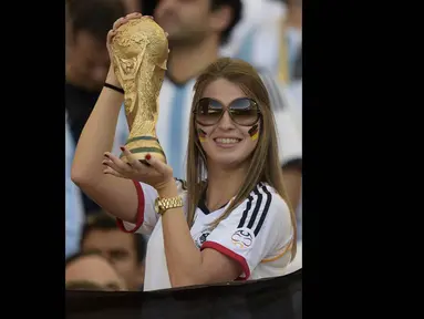 Seorang wanita suporter Jerman tampak memegang trofi Piala Dunia, Brasil, Senin (14/7/14). (AFP/JUAN MABROMATA)