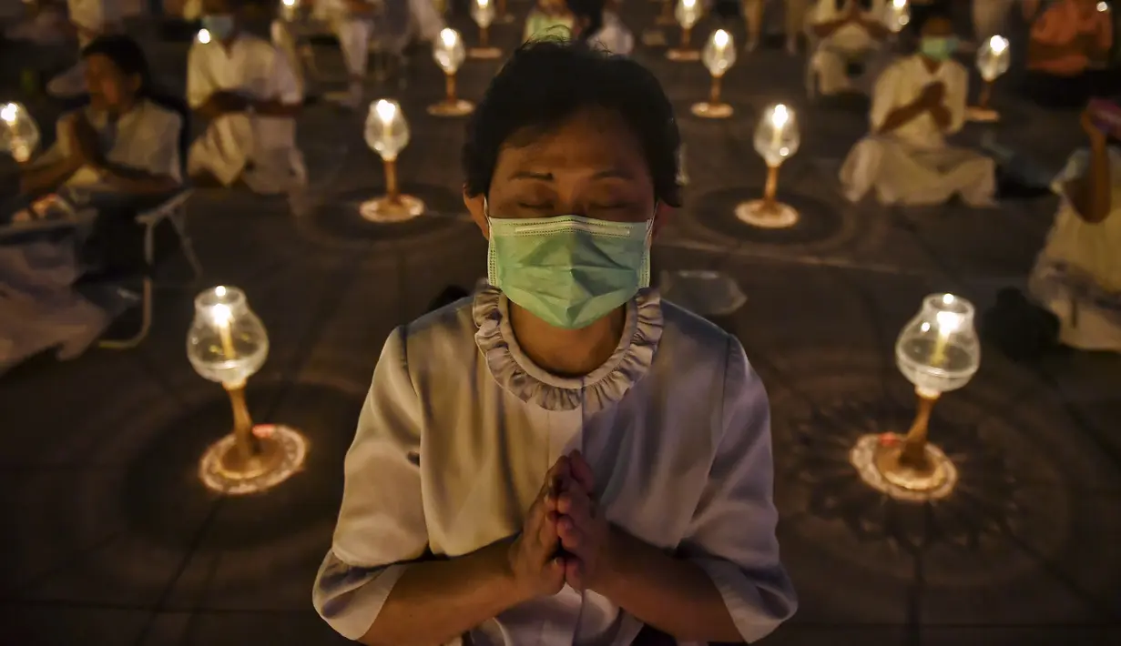 Umat Buddha mengenakan masker saat berdoa bersama di kuil Buddha Wat Dhammakaya, Bangkok (31/1/2020). Pemerintah Thailand mengumumkan 14 orang terkonfirmasi infeksi virus corona.Thailand memiliki jumlah kasus terbesar kedua di luar China. (AFP Photo/Lillian Suwanrumpha)