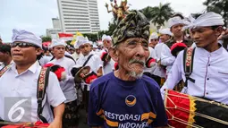 Seorang kakek dari simpatisan Partai NasDem mengikuti pawai ogoh-ogoh saat aksi Kita Indonesia di Bundaran HI, Jakarta, Minggu (04/12). Aksi tersebut adalah acara perayaan kegembiraan atas keberagaman dan kebangsaan Indonesia. (Liputan6.com/Fery Pradolo)