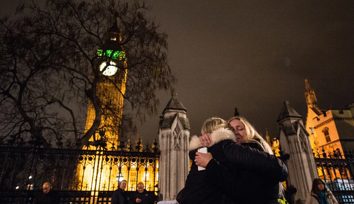 Pengunjuk rasa berpelukan usai pemungutan pemerintah Inggris pada aksi militer terhadap Negara Islam (IS) Suriah di London (2/11). Parlemen Inggris menyetujui serangan udara terhadap kelompok ISIS di Suriah. (AFP PHOTO/CHRIS Ratcliffe)
