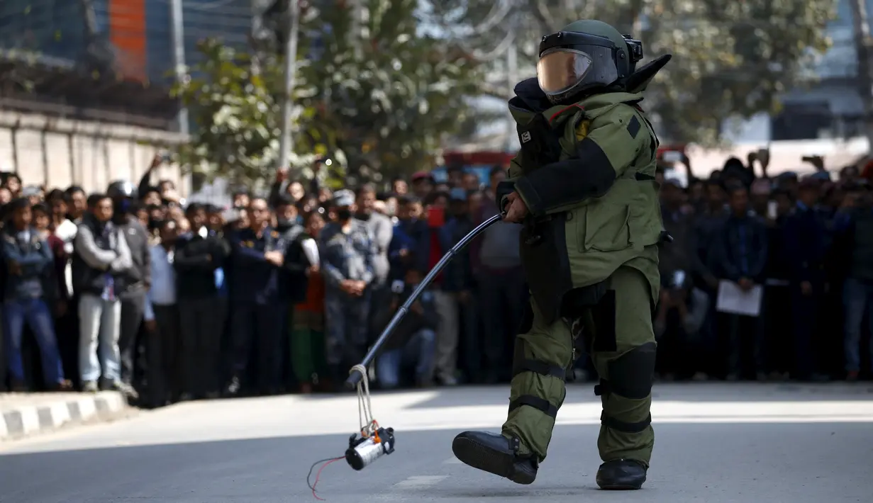  Seorang anggota tim penjinak bom membawa benda mencurigakan yang menghebohkan warga di kompleks kantor Singha Durbar, Kathmandu , Nepal, (1/3). Warga sekitar mendadak heboh karena mengira benda tersebut adalah sebuah bom. (REUTERS / Navesh Chitrakar)