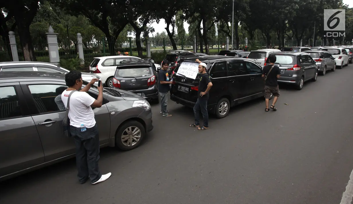 Sejumlah sopir taksi online berpose saat demo di Jalan Medan Merdeka Barat, Jakarta, Rabu (14/2). Para pengemudi meminta Menteri Perhubungan Budi Karya untuk menghapus Permenhub Nomor 108 Tahun 2017. (Liputan6.com/Arya Manggala)