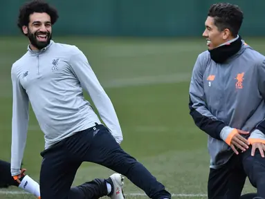 Penyerang Liverpool, Mohamed Salah (kiri) dan Roberto Firmino melakukan pemanasan saat latihan di Melwood Training Ground, Liverpool, Inggris (5/3). Liverpool akan melawan Porto pada leg kedua babak 16 besar Liga Champions. (AFP Photo/Anthony Devlin)