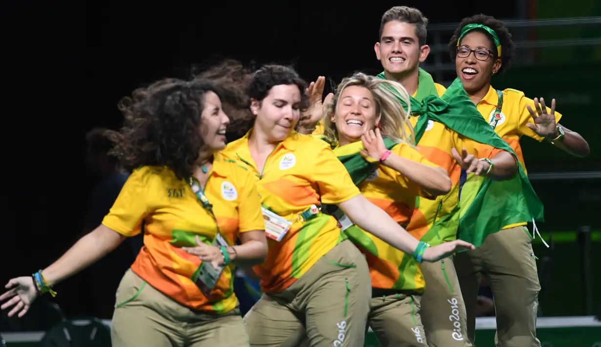 Sejumlah relawan menari untuk menghibur penonton sebelum dimulainya kompetisi cabang angkat besi Olimpiade 2016 di Rio de Janeiro, 15 Agustus 2016. (AFP PHOTO/Goh Chai HIN)