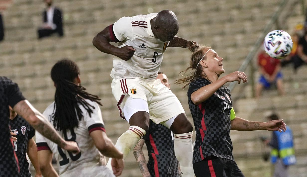 Striker Belgia, Romelu Lukaku (tengah) melepaskan sundulan di samping bek Kroasia, Domagoj Vida (kanan) dalam laga uji coba menjelang berlangsungnya Euro 2020 di King Baudouin Stadium, Brussels, Minggu (6/6/2021). Belgia menang 1-0 atas Kroasia. (AP/Francisco Seco)