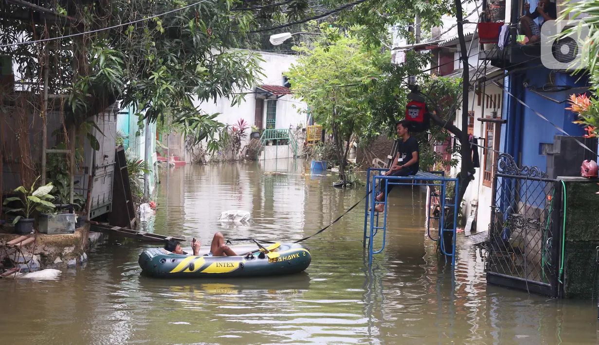 Seorang warga beristirahat di perahu karet saat banjir melanda perumahan Periuk Damai, Tangerang, Banten, Selasa (22/2/2021). Ratusan rumah masih terendam banjir sampai menyentuh ke atap rumahnya. (Liputan6.com/Angga Yuniar)