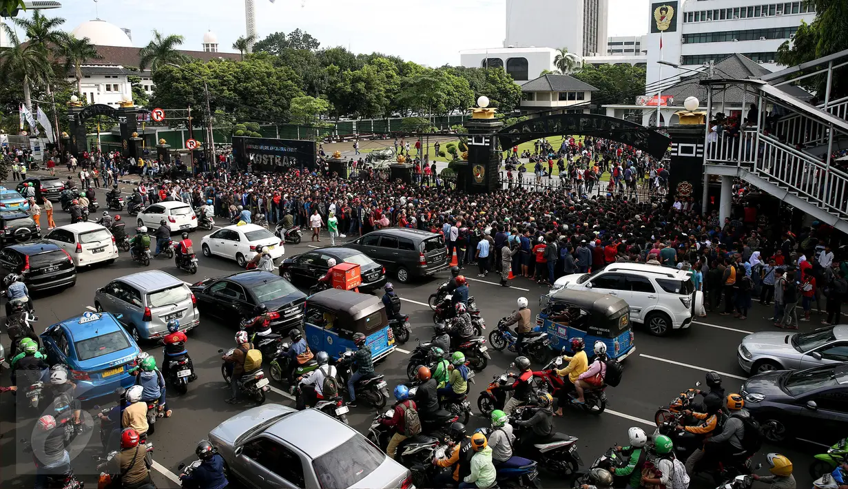 Kendaraan melintas sementara pembeli tiket Final Piala AFF mengantre masuk ke Markas Garnisun Tetap 1, Gambir, Jakarta, Selasa (13/12). Final Piala AFF akan dihelat di Stadion Pakansari, Bogor pada Rabu, 14 Desember mendatang. (Liputan6.com/Johan Tallo)