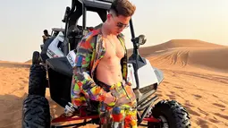 Dengan latar belakang foto berupa gurun pasir, Varrel tampil dengan busana berwarna-warni  dan memamerkan otot perutnya yang sixpack.  (Instagram/bramastavrl)