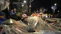 Orang-orang berkemah di depan Istana Westminster pada malam pemakaman Ratu Elizabeth II di London, Minggu, 18 September 2022. Pemakaman Ratu Elizabeth II, raja terlama di Inggris, berlangsung pada Senin (19/9). (AP Photo/Christophe Ena)