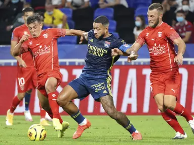 Penyerang Lyon, Memphis Depay, berebut bola dengan pemain Nimes pada laga lanjutan Liga Prancis di Stadion Groupama, Sabtu (19/9/2020) dini hari WIB. Lyon bermain imbang 0-0 atas Nimes. (AP Photo/Laurent Cipriani)
