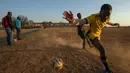 Seorang pemain berusaha mengontrol bola saat bertanding pada laga persahabatan di lapangan yang berdebu di Soweto, Afrika Selatan, Rabu (16/6/2021).  Sejumlah warga bermain bola di lapangan berdebu di Soweto, Afrika Selatan. (AP Photo/Themba Hadebe)
