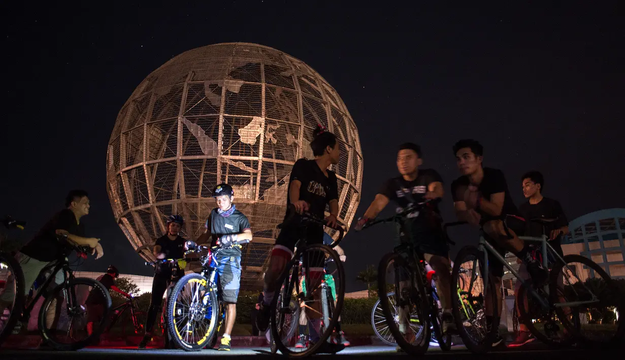 Sejumlah pengendara sepeda berkumpul di depan instalasi bola dunia disebuah mal di Manila saat memperingati Earth Hour Internasional, Manila (25/3). (AFP/Neol Celis)